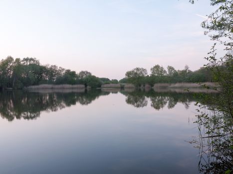 reeds in the distance of this river as the sunsets to the left over the lake in the country in the spring in the UK