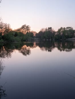 beautiful hortizontal portrait of a lake with tree reflections during sunset glorious colors and mood feeling lots of peace and calm in spring heat of nature