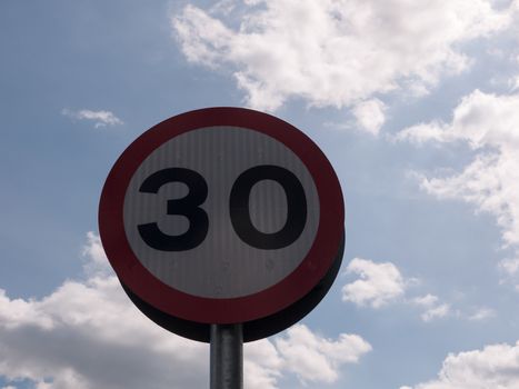 a road traffic sign with a sky background saying 30 speed limit near school accident crash cars fast and slow warning police spring light