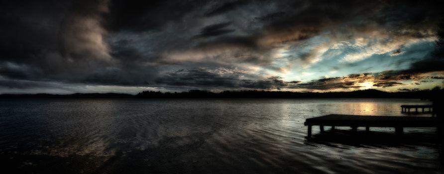 Sunset over the Lake of Varese with dramatic clouds and pier in the foreground