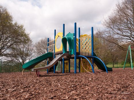 A Children Playground Climbing Frame Multicolored and with various slides for fun and games on wood chip safety outside park