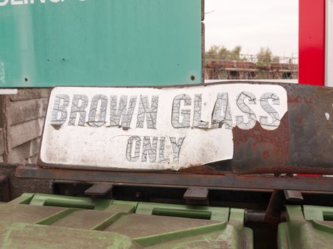 a sign saying brown glass only retro vintage worn faded tattered outside near recycling plant and green bins clean environment council england