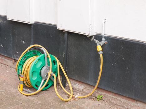 a rolled up hose plugged into the tap at the side of a house with no water running hosepipe ban uk heat save summer no people wall