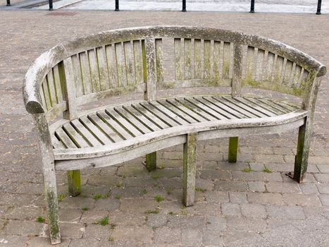 an empty wood bench outside on the pavement bricks with moss and wear and age olden no people stunning cool nice angle empty alone public park space sitting sleeping rough