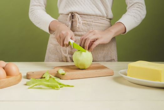 House wife wearing apron making. Steps of making cooking apple cake. Cutting green apple.