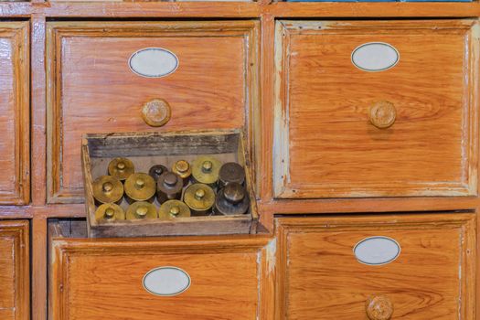 Close up of a very old pharmacy medicine drawer cabinet with small brass weights