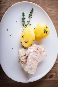 Steamed fish and potato on a white plate