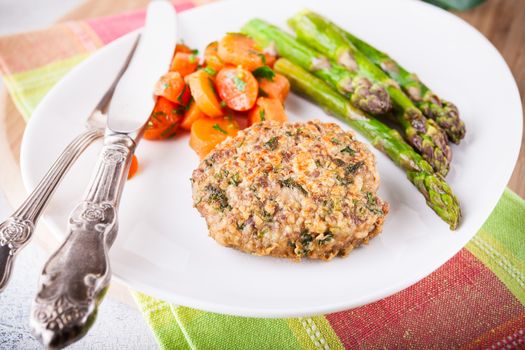 Meat rissole with glazed carrots, asparagus on the plate 