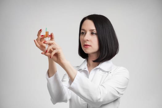 the beautiful woman the doctor with the syringe on a white background