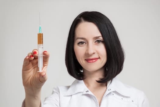 the beautiful woman the doctor with the syringe on a white background