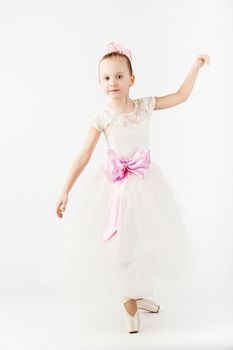 Beautiful ballet dancer isolated on white background. Slender little ballerina girl in white dress and in pointe shoes