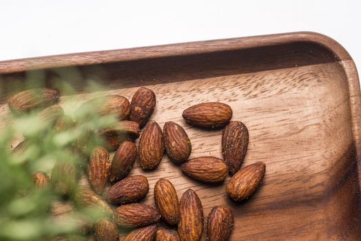 Toasted almonds  in a wood sish over a black board.