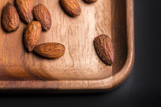 Toasted almonds  in a wood sish over a black board.