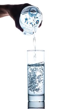 Drinking water is poured into a glass from bottle