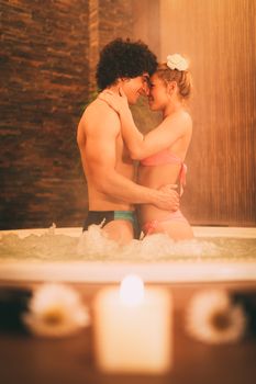 Beautiful young couple enjoying in a hot tub at the spa center.