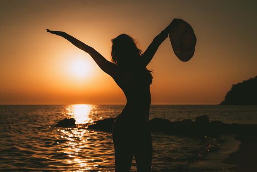 Silhouette of  happy girl enjoying at sunset on the beach.