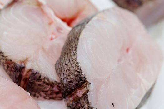 fresh pieces of hake on showcase of seafood market