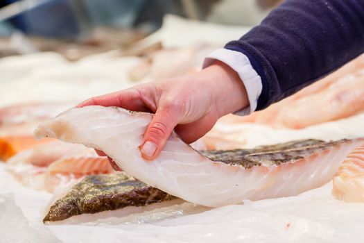 Fishmonger holding a piece of fresh fish in a market