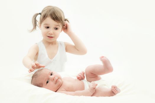 elder sister and the younger newborn child on a white background