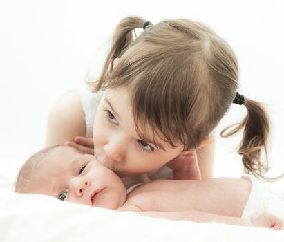 elder sister and the younger newborn child on a white background