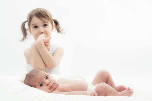 elder sister and the younger newborn child on a white background