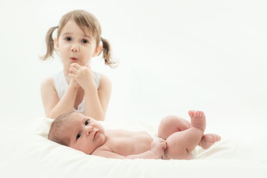 elder sister and the younger newborn child on a white background