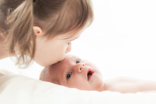 elder sister and the younger newborn child on a white background