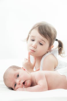 elder sister and the younger newborn child on a white background