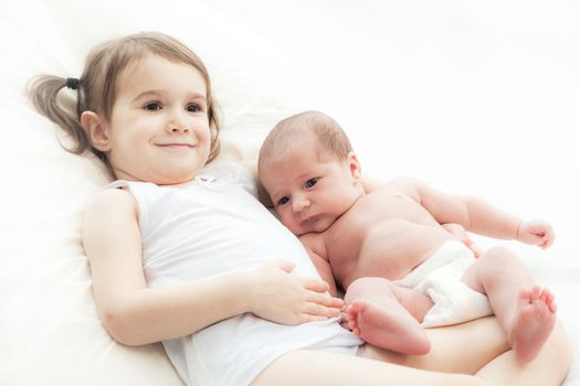 elder sister and the younger newborn child on a white background