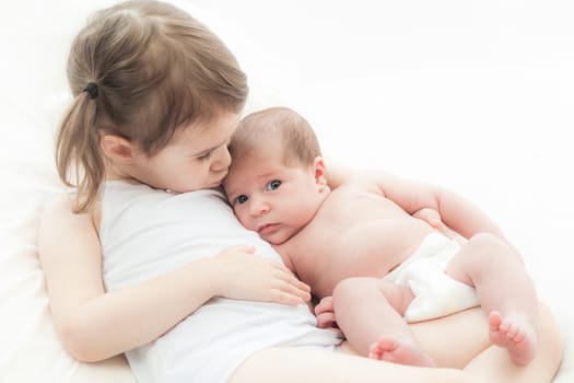 elder sister and the younger newborn child on a white background