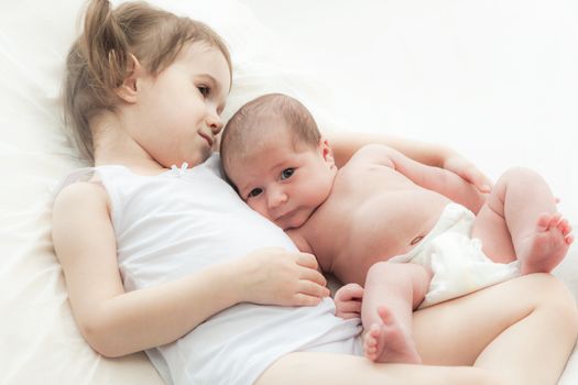 elder sister and the younger newborn child on a white background