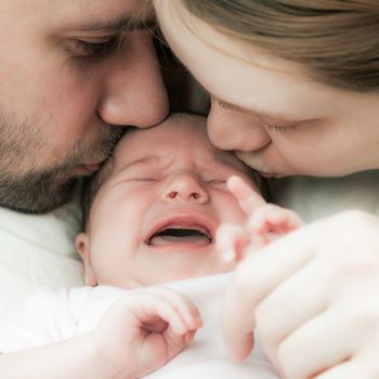 parents kiss the small newborn child a fragment