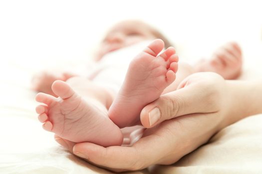 the mother's hand holds legs of the newborn child