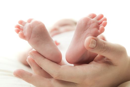 the mother's hand holds legs of the newborn child