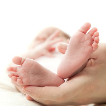 the mother's hand holds legs of the newborn child