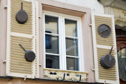 Windows with shutters and poelons hang on in front of a restaurant in the Grand Duchy of Luxembourg