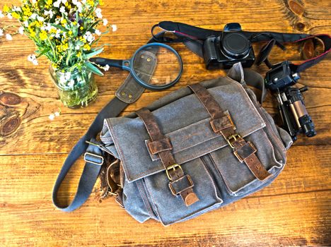 Bleu Satchel With Camera, Tripod and Magnefying Glass Sitting on Wooden Table