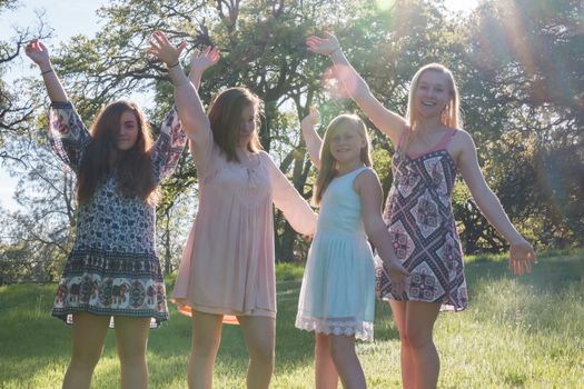 Group of Girls Standing With Arms Raised and Sunlight Overhead