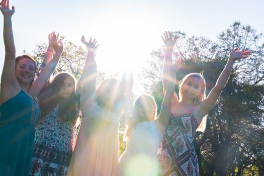 Group of Girls Standing With Arms Raised and Sunlight Overhead