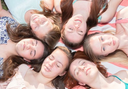 Young Girls Laying on the Ground Smiling and Looking up, Some With Eyes Closed