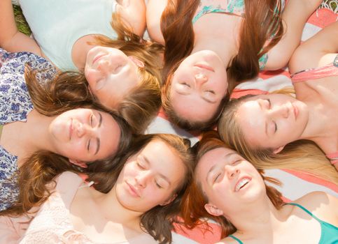 Young Girls Laying on the Ground Smiling and Looking up, Some With Eyes Closed