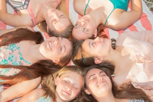 Young Girls Laying on the Ground Smiling and Looking up, Some With Eyes Closed