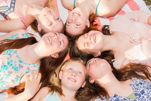 Young Girls Laying on the Ground Smiling and Looking up, Some With Eyes Closed