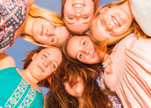 Young Girls With Heads Together Looking Down With Blue Sky in the Bakground