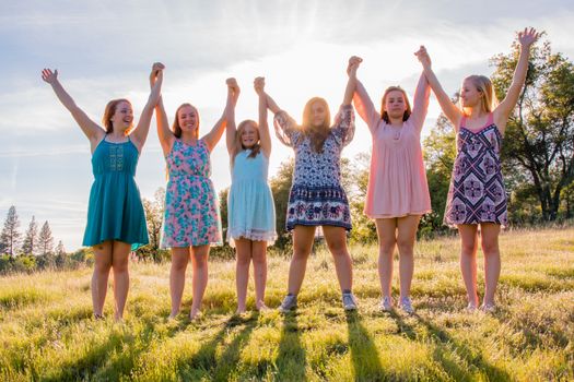 Group of Girls Standing With Arms Raised and Sunlight Overhead