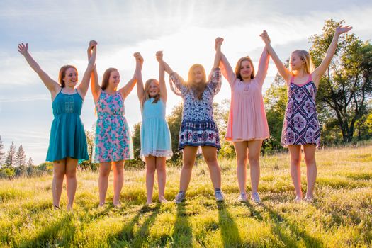 Group of Girls Standing With Arms Raised and Sunlight Overhead