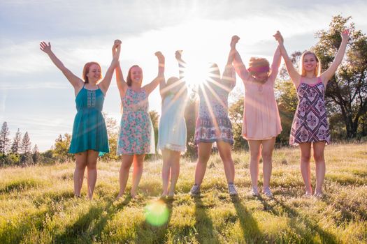 Group of Girls Standing With Arms Raised and Sunlight Overhead