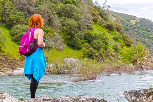 Young Girl Standing on Rocks Near Fast River