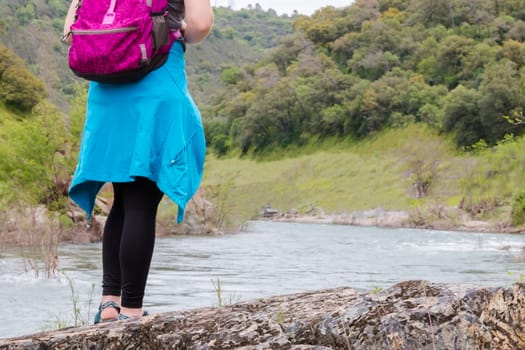 Young Girl Standing on Rocks Near Fast River