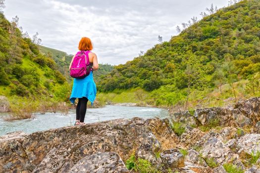 Young Girl Standing on Rocks Near Fast River